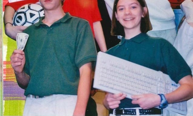 The same picture of Katherine Nieman in the 8th grade holding a keyboard, but next to her, an 8th grade boy stands holding a five dollar bill.